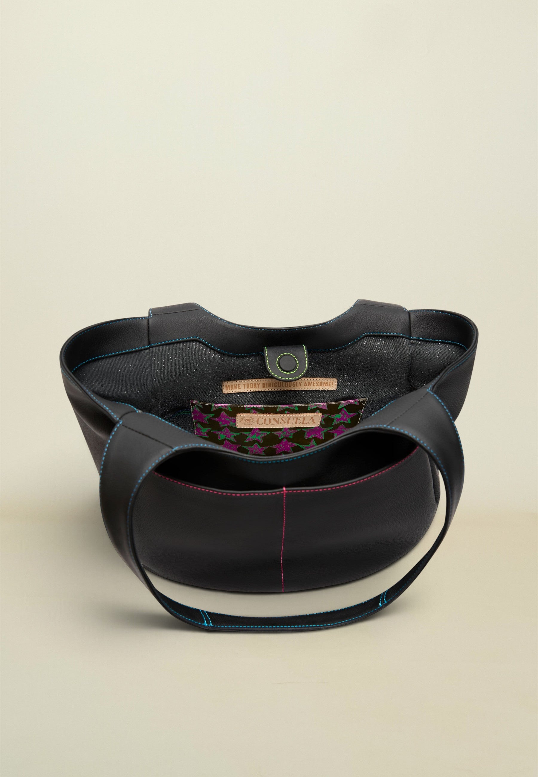 A black leather shoulder bag with a structured, rounded silhouette, featuring contrasting blue and pink stitching, a gold-tone metal ring closure, and a patterned interior label.