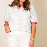 Woman wearing Emmie white pointelle short sleeve sweater with hot pink trim and white wide-leg pants.
