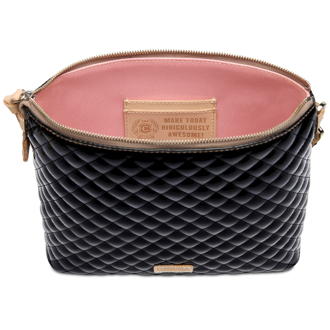 Black quilted handbag with pink interior and motivational tag on a white background