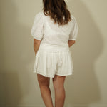 Person wearing a white outfit against a plain wall