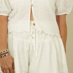 Woman wearing a white outfit against a plain background
