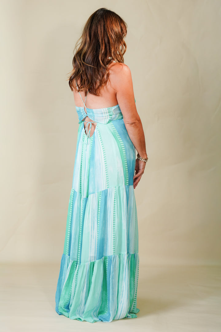 Woman wearing a long, light blue and green striped dress against a plain background