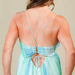 Woman wearing a long, patterned dress with a beige background
