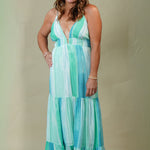 Woman wearing a long, patterned dress against a plain background