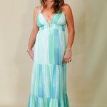 Woman wearing a green and blue patterned dress against a beige background