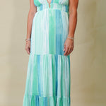 Woman wearing a green and blue striped dress against a beige background