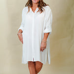 Woman wearing a white dress against a beige background