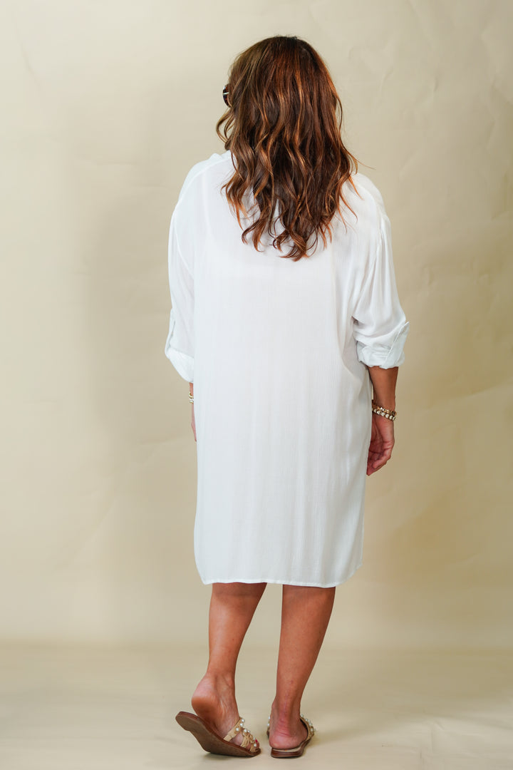 Back view woman wearing a white dress against a beige background
