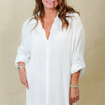 Woman wearing a white shirt dress against a beige background