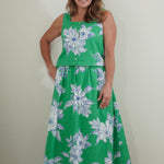 Woman wearing a green floral dress against a plain background