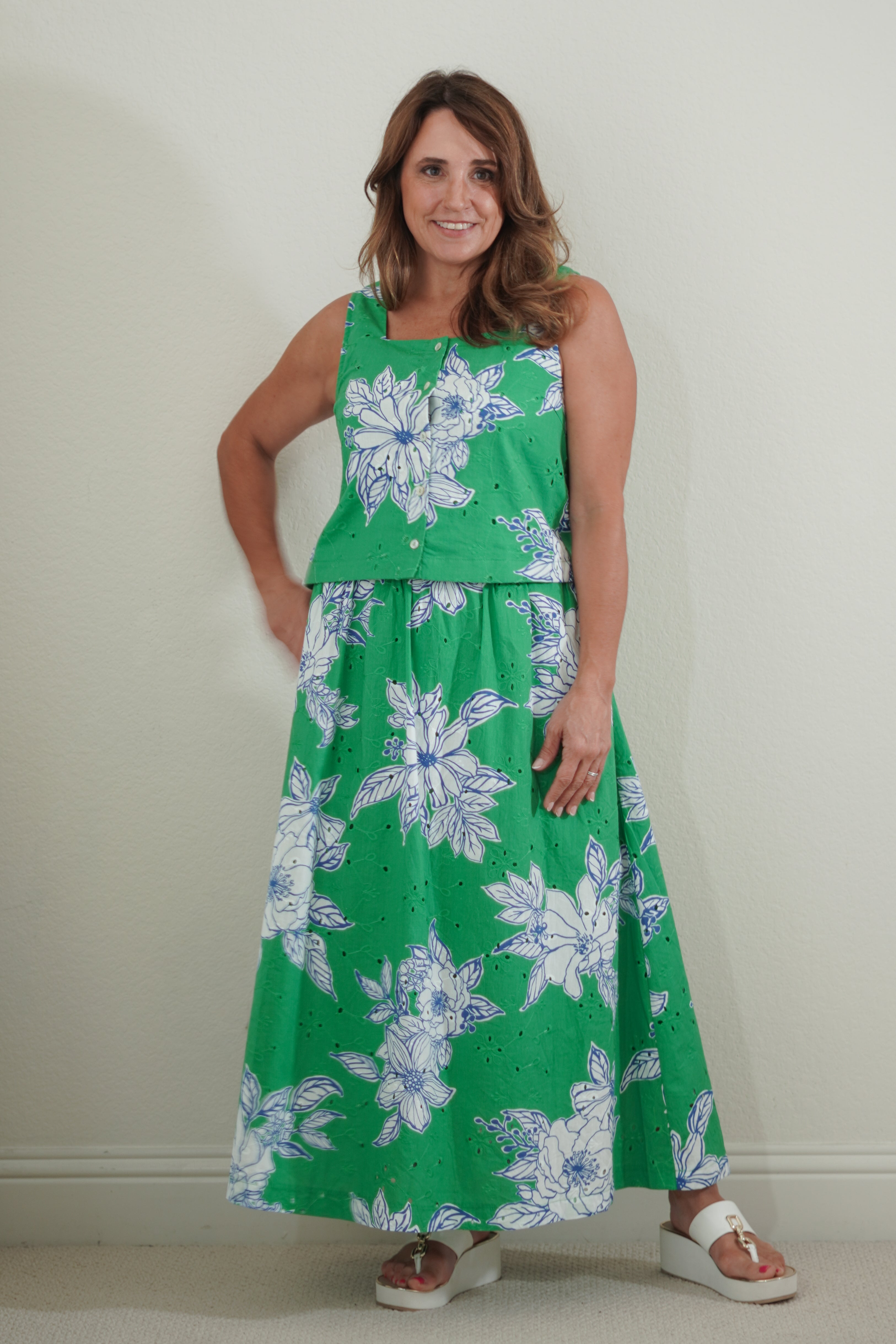 Woman wearing a green floral dress against a plain background