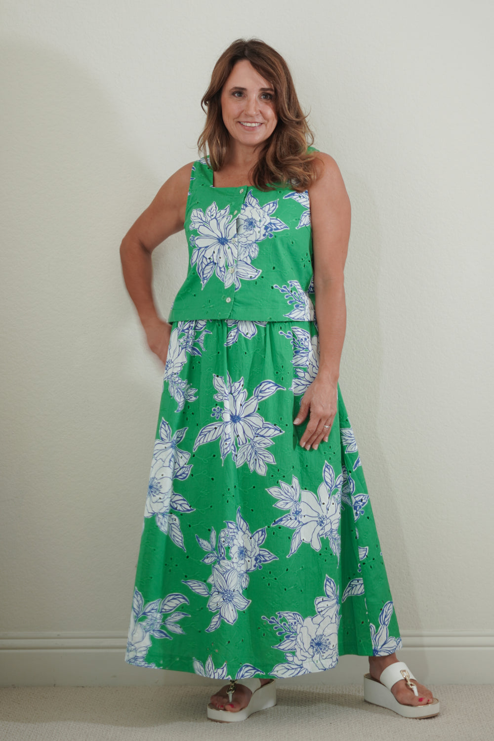 Woman wearing a green floral dress against a plain background