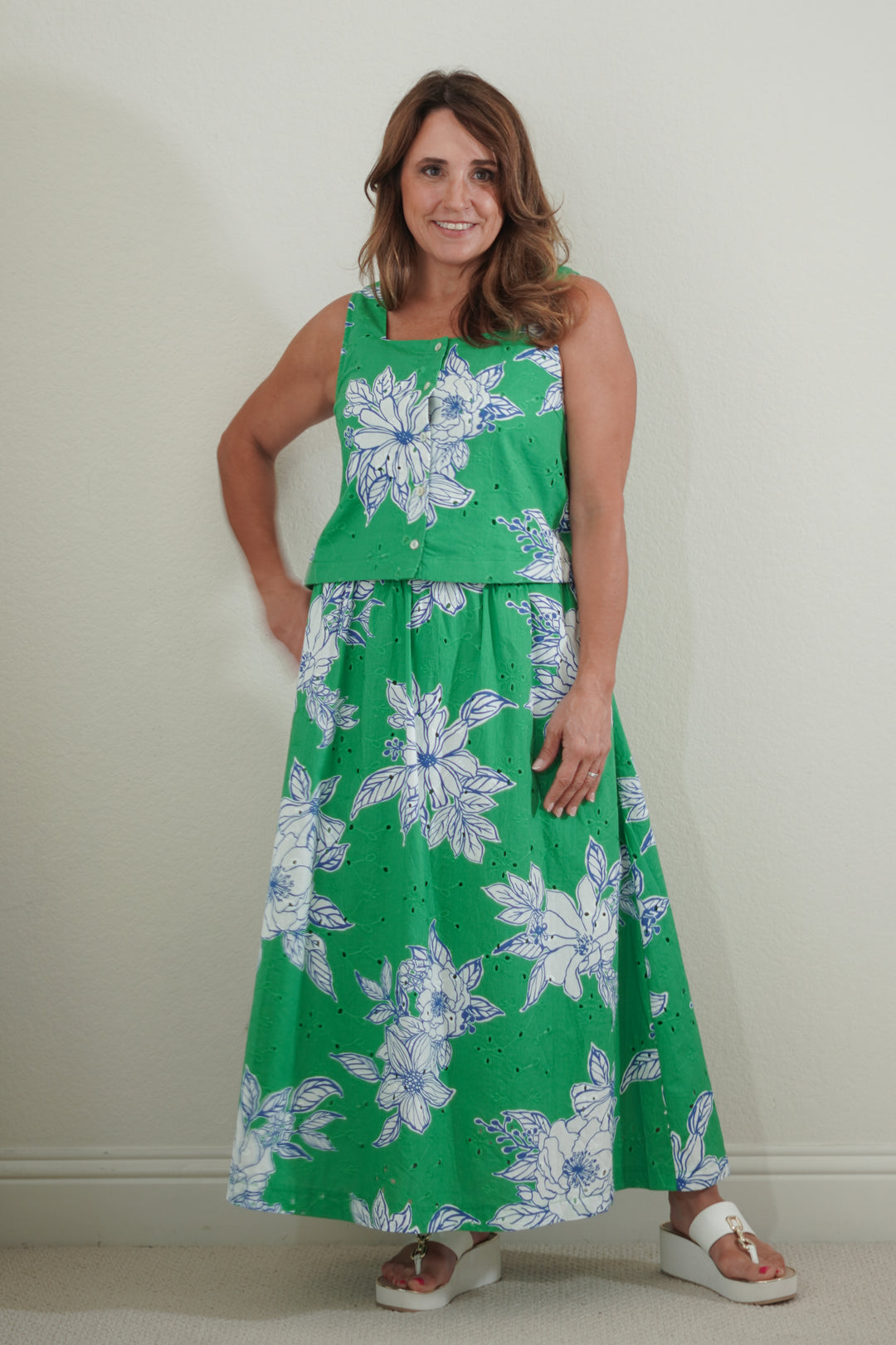 Woman wearing a green floral dress against a plain background
