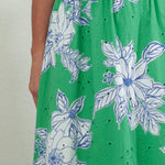 Woman wearing a green floral dress against a plain background