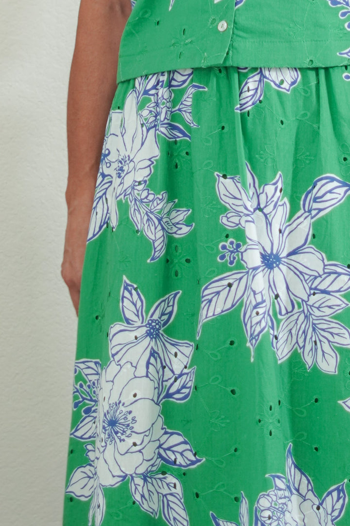 Woman wearing a green floral dress against a plain background
