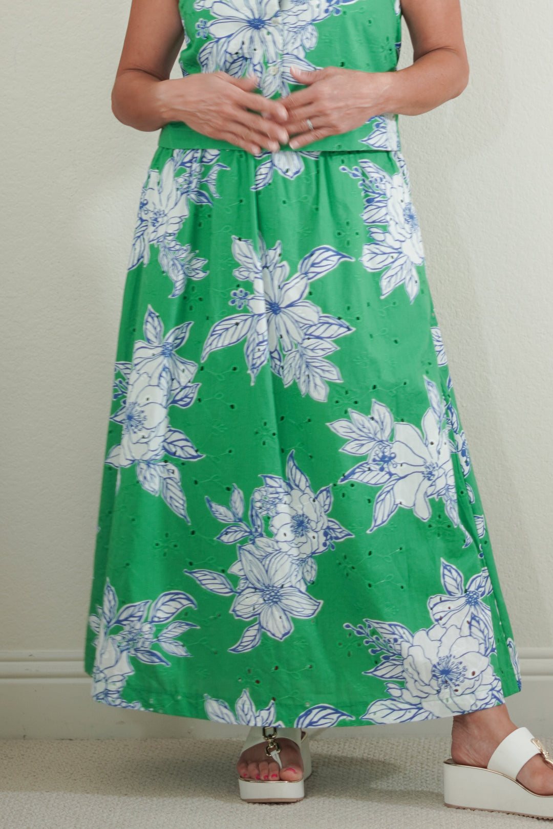 Woman wearing a green dress with floral pattern against a plain background
