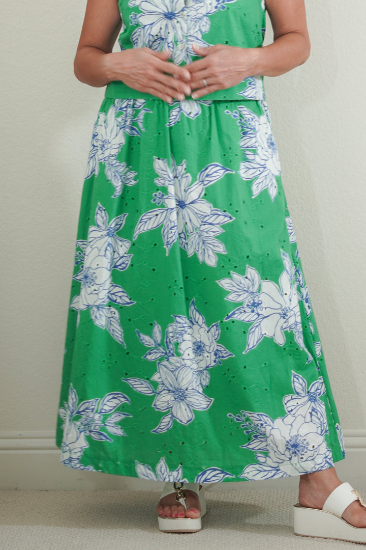 Woman wearing a green dress with floral pattern against a plain background