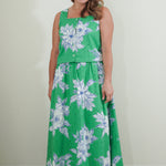 Woman wearing a green floral dress against a plain background