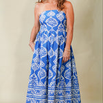 Woman wearing a blue strapless dress with white patterns on a beige background