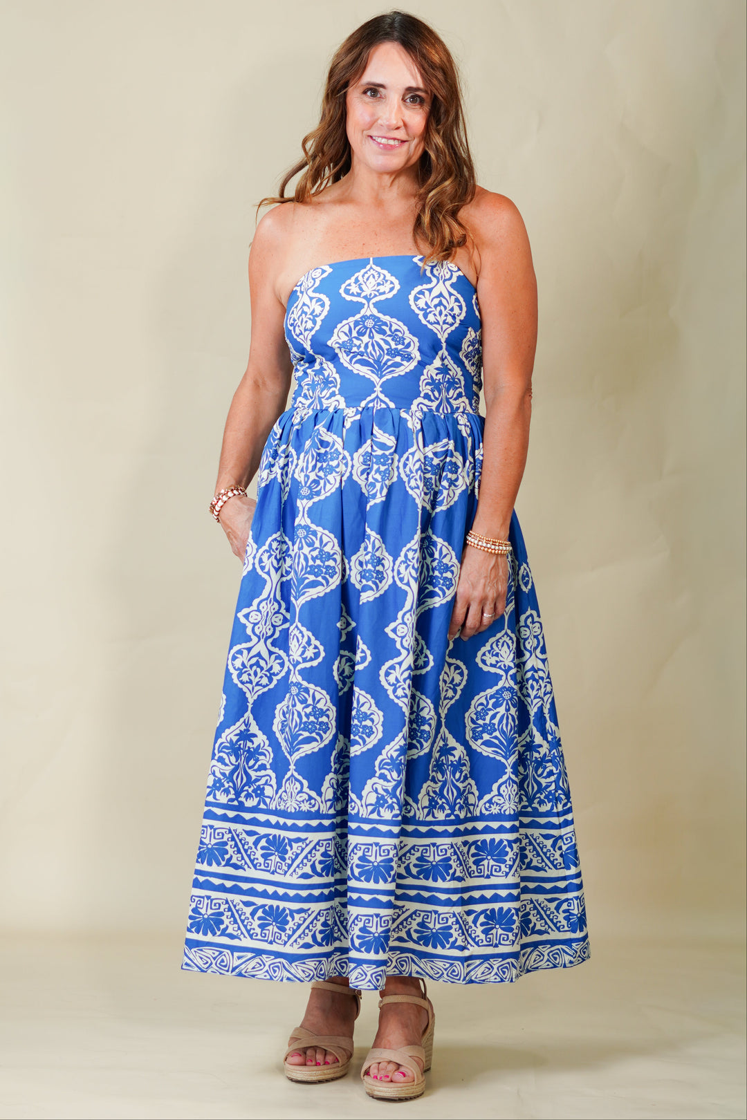 Woman wearing a blue strapless dress with white patterns on a beige background