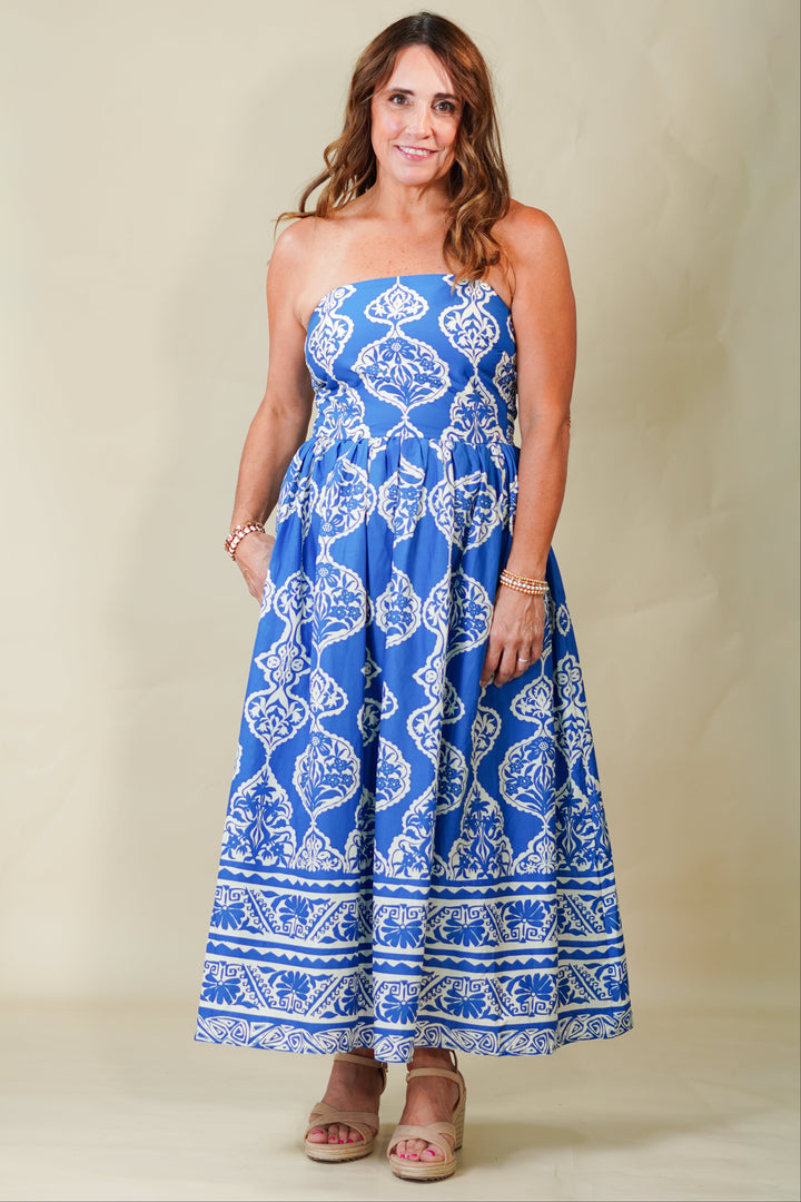 Woman wearing a blue strapless dress with white patterns on a beige background