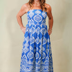 Woman wearing a blue and white patterned dress against a plain background