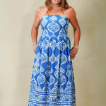 Woman wearing a blue strapless dress with white patterns on a beige background