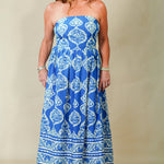 Woman wearing a blue strapless dress with white patterns on a beige background