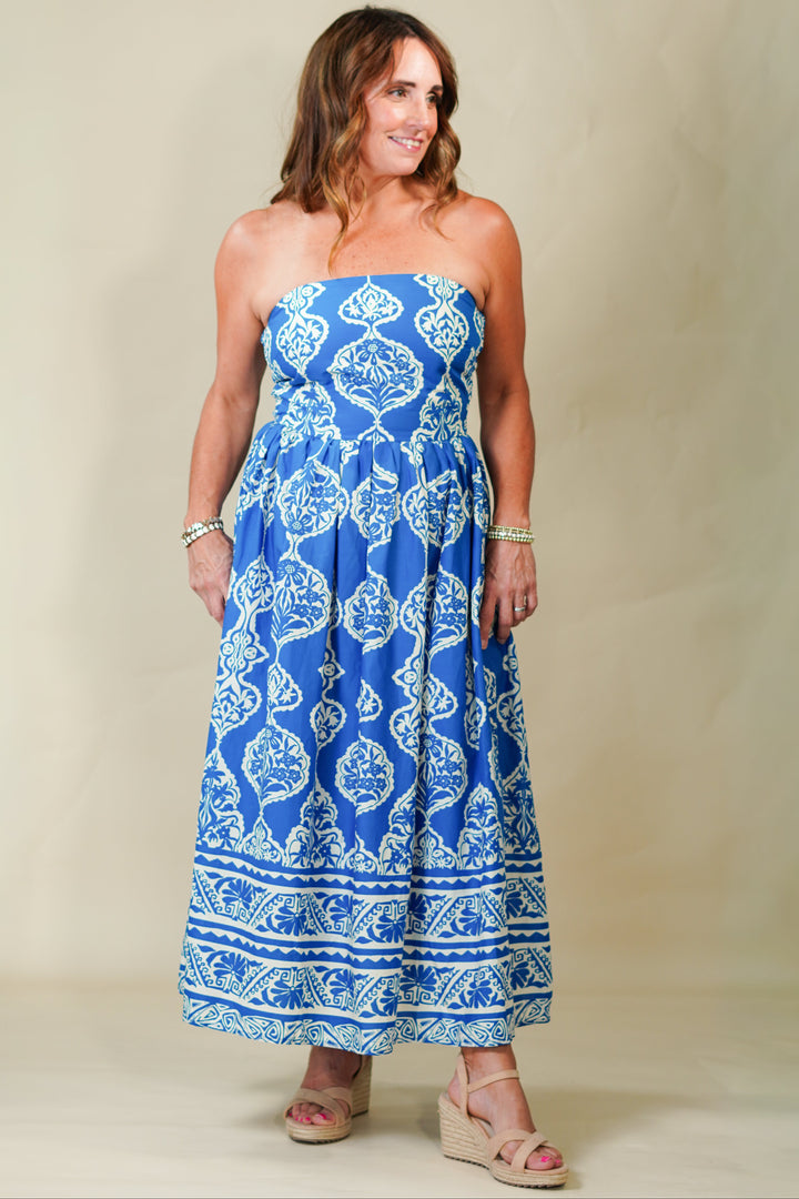 Woman wearing a blue strapless dress with white patterns on a beige background