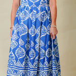 Woman wearing a blue strapless dress with white patterns on a beige background