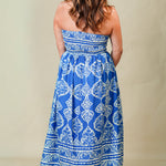 Woman wearing a blue and white patterned strapless dress against a beige background