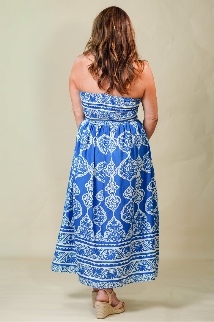 Woman wearing a blue and white patterned strapless dress against a beige background