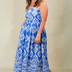 Woman wearing a blue and white patterned strapless dress on a beige background