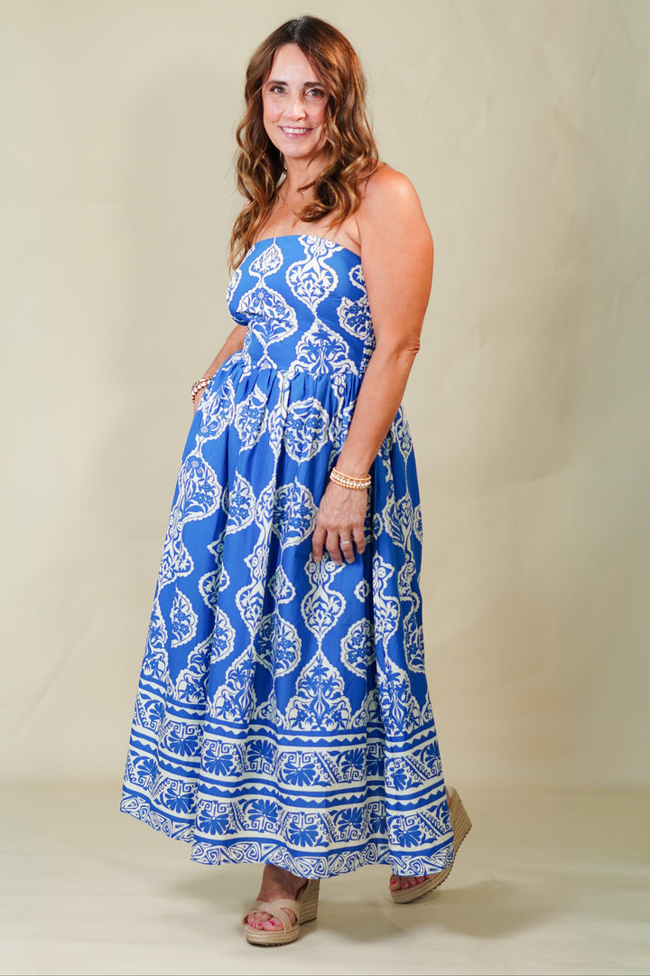 Woman wearing a blue and white patterned strapless dress on a beige background