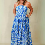Woman wearing a blue strapless dress with white patterns on a plain background