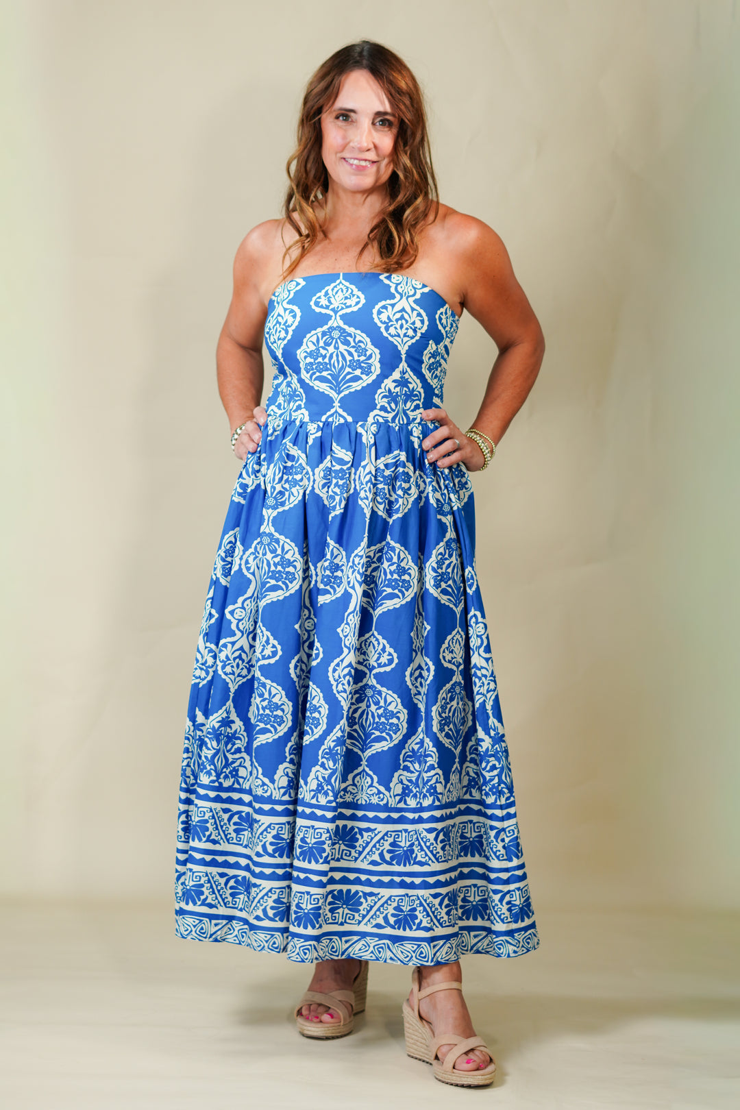 Woman wearing a blue strapless dress with white patterns on a plain background