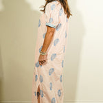 Side view of Entro blush pink botanical block print maxi dress showing puff sleeves, striped cuff trim, and side slit hem detail on model