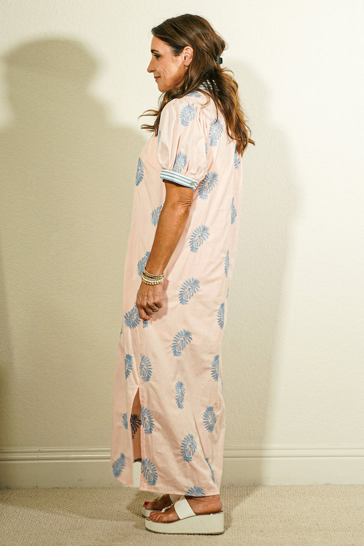 Side view of Entro blush pink botanical block print maxi dress showing puff sleeves, striped cuff trim, and side slit hem detail on model