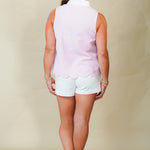 Woman wearing a sleeveless pink top and white shorts on a beige background