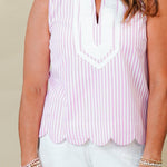 Woman wearing a light pink sleeveless top and white shorts against a beige background