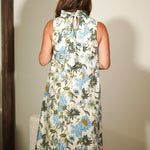 Woman wearing a floral dress standing in front of a mirror.