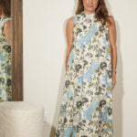Woman wearing a floral dress standing in front of a mirror.