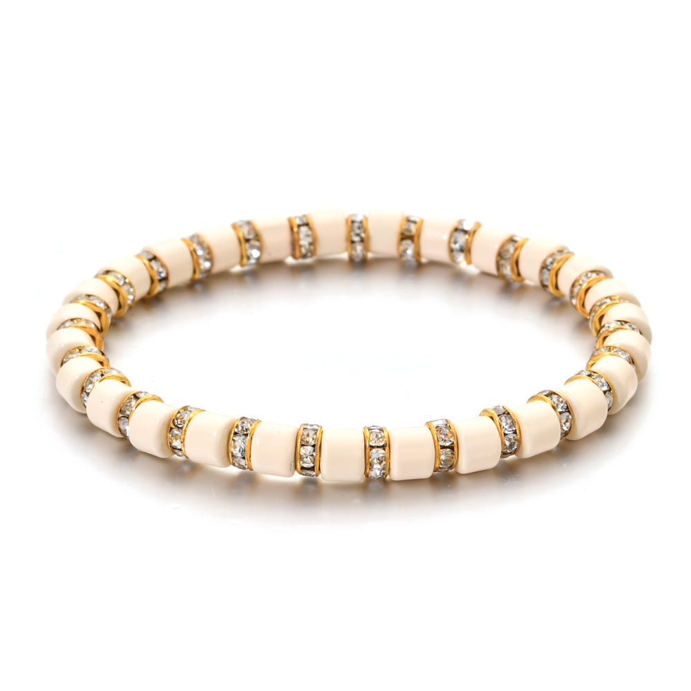 Beige bracelet with gold and clear gemstone accents on a white background