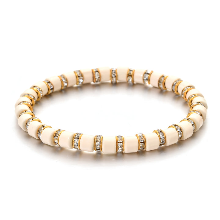 Beige bracelet with gold and clear gemstone accents on a white background