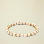 Beige bracelet with gold and clear gemstone accents on a white background