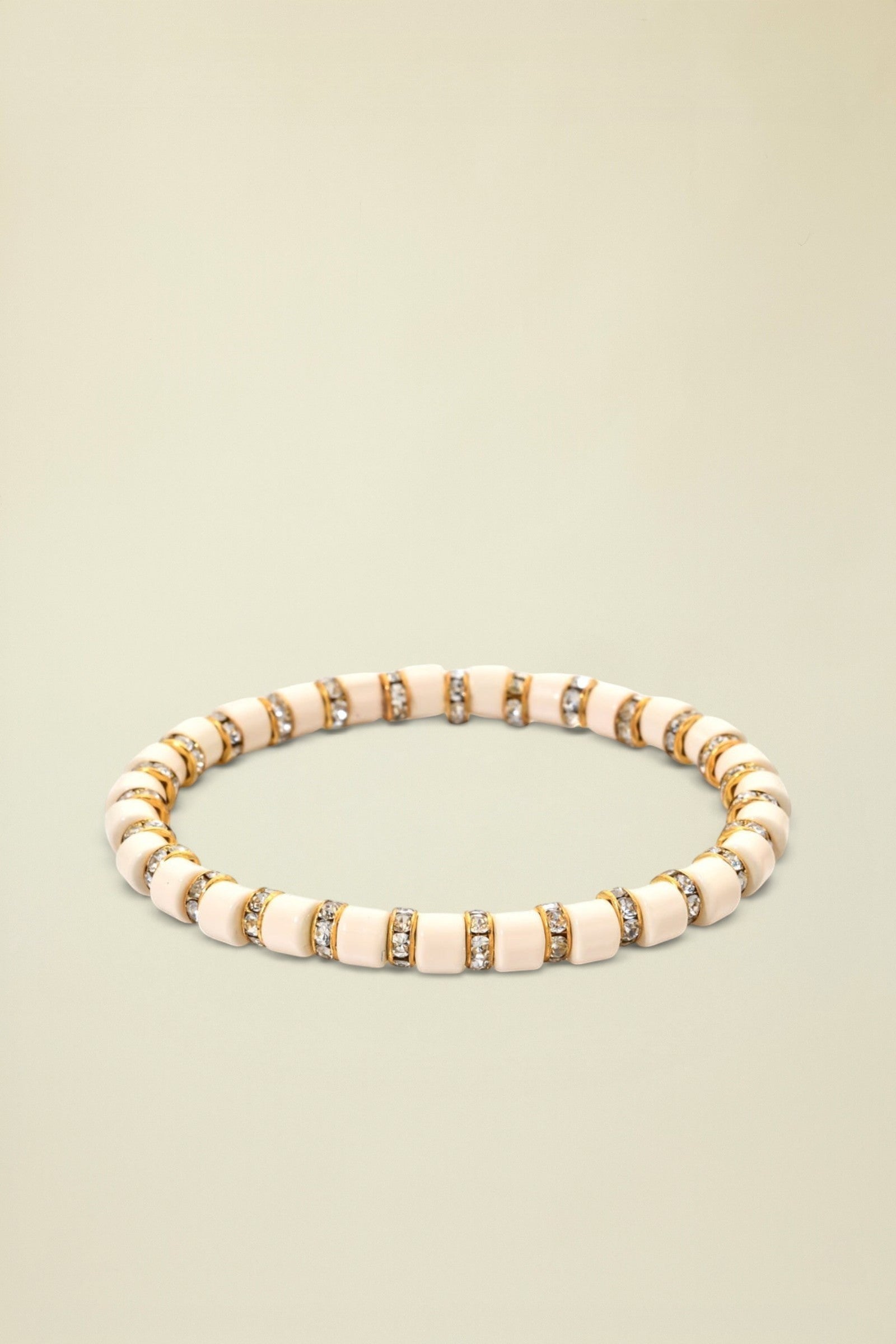 Beige bracelet with gold and clear gemstone accents on a white background