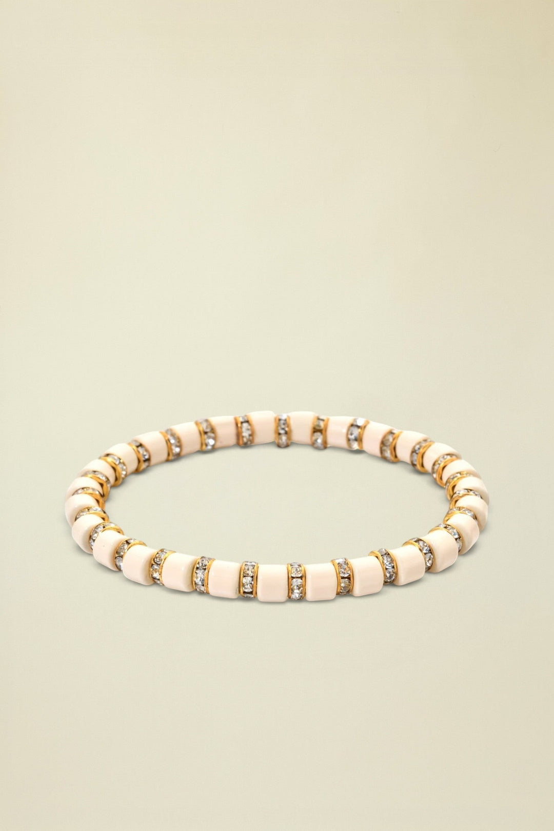 Beige bracelet with gold and clear gemstone accents on a white background