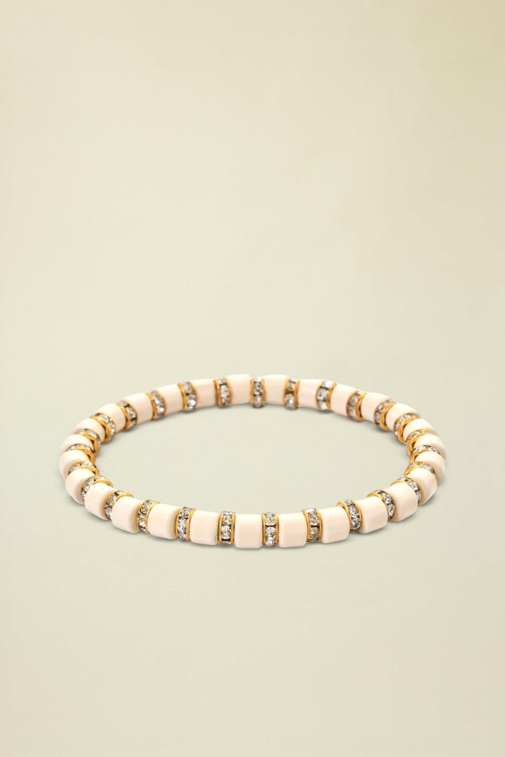 Beige bracelet with gold and clear gemstone accents on a white background