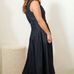 side view of a woman wearing a dark blue sleeveless dress against a plain background