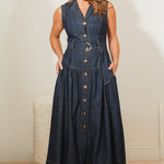 Woman wearing a long denim dress with a belt against a plain background